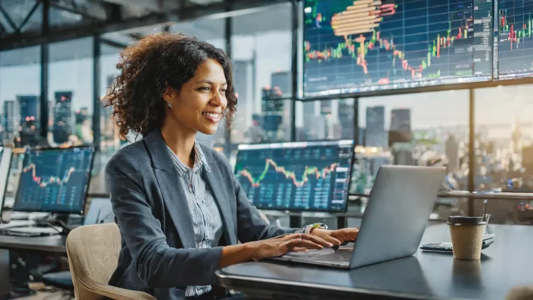 In this picture a woman working on forex funded account on laptop in her office